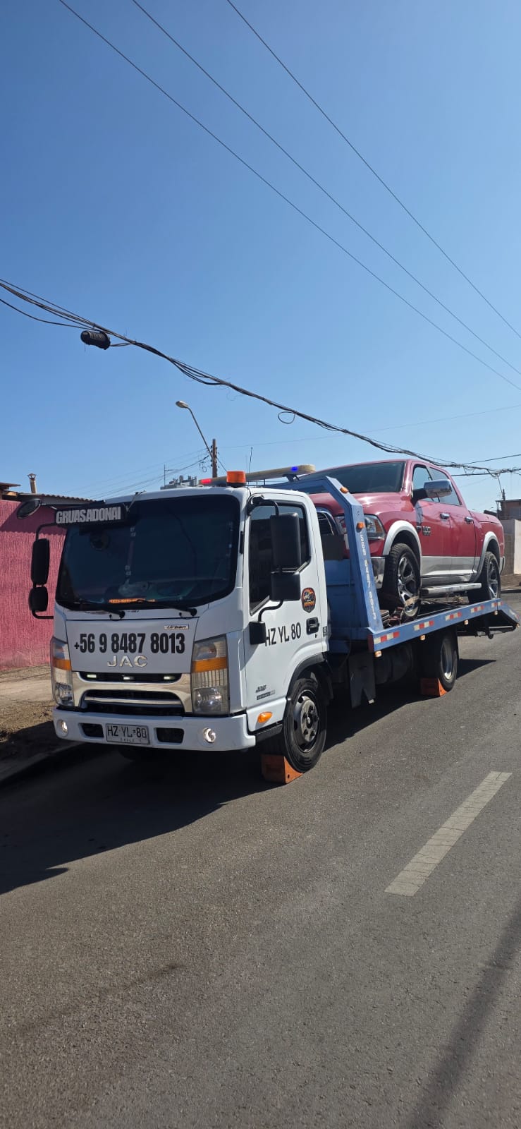 Grúa cama trasladando camioneta roja en zona urbana de Antofagasta